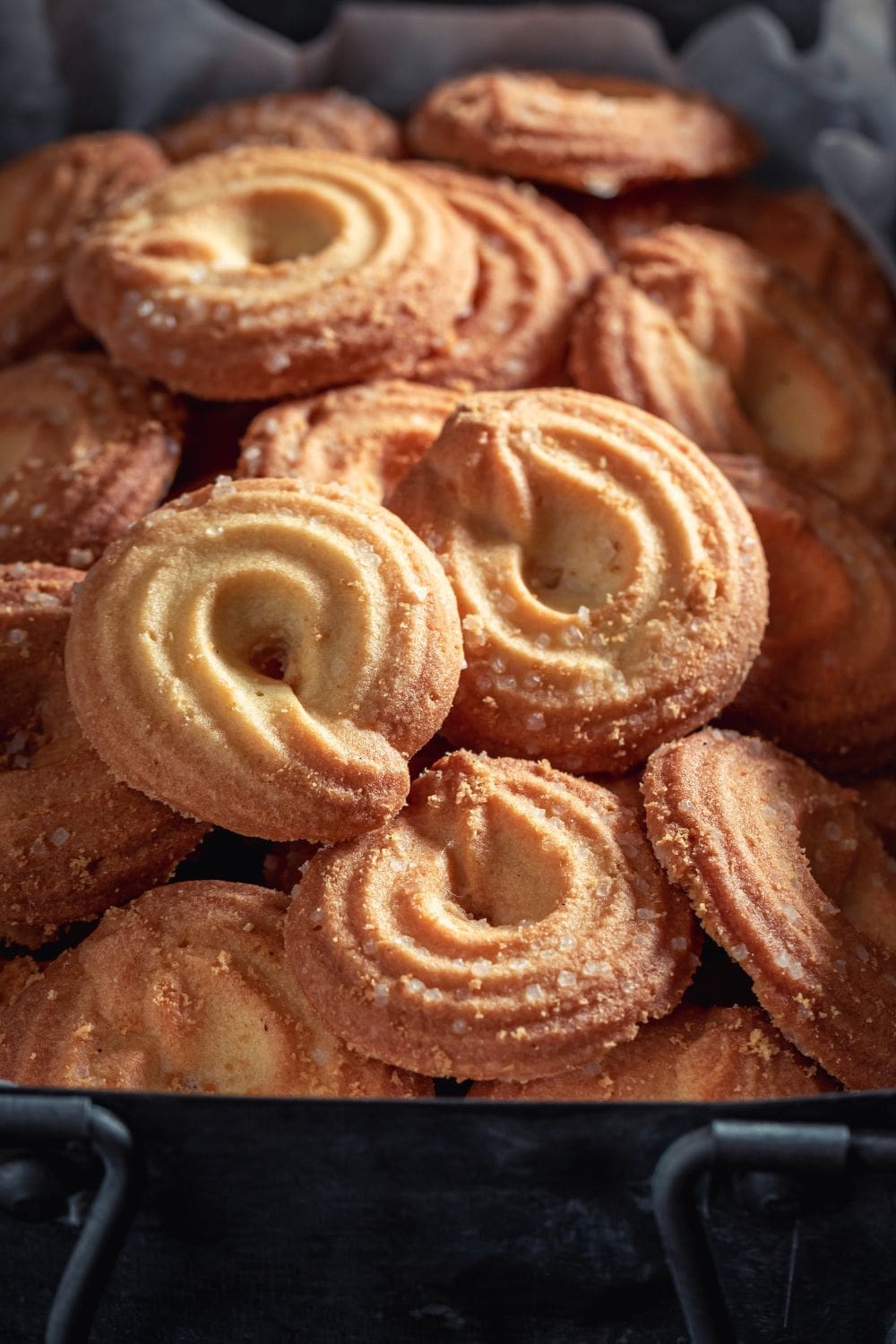A close-up photo of a pile of homemade vegan danish cookies on a baking sheet.