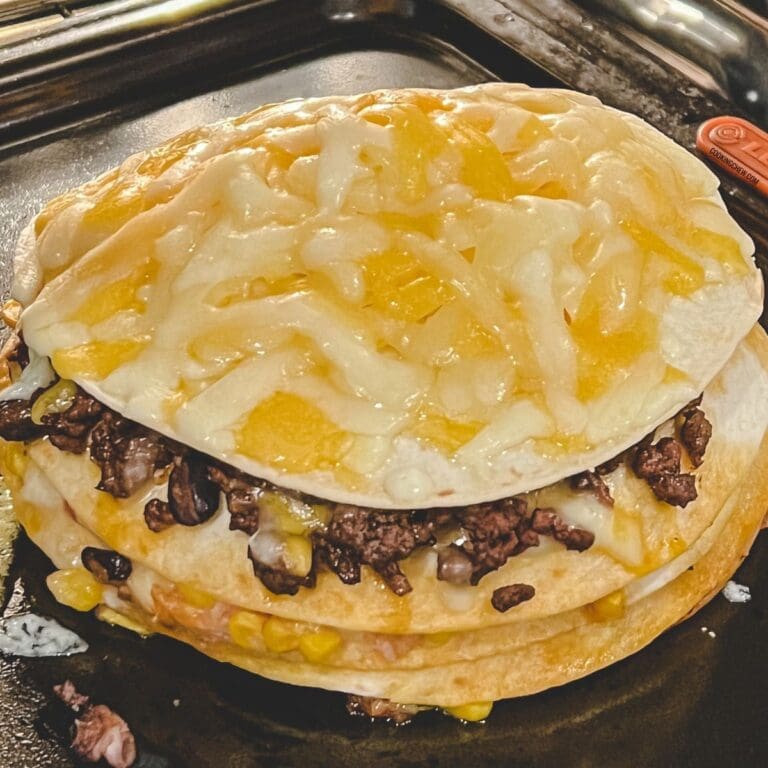 A close-up photo of a double-decker mexican tortilla casserole on a baking sheet.