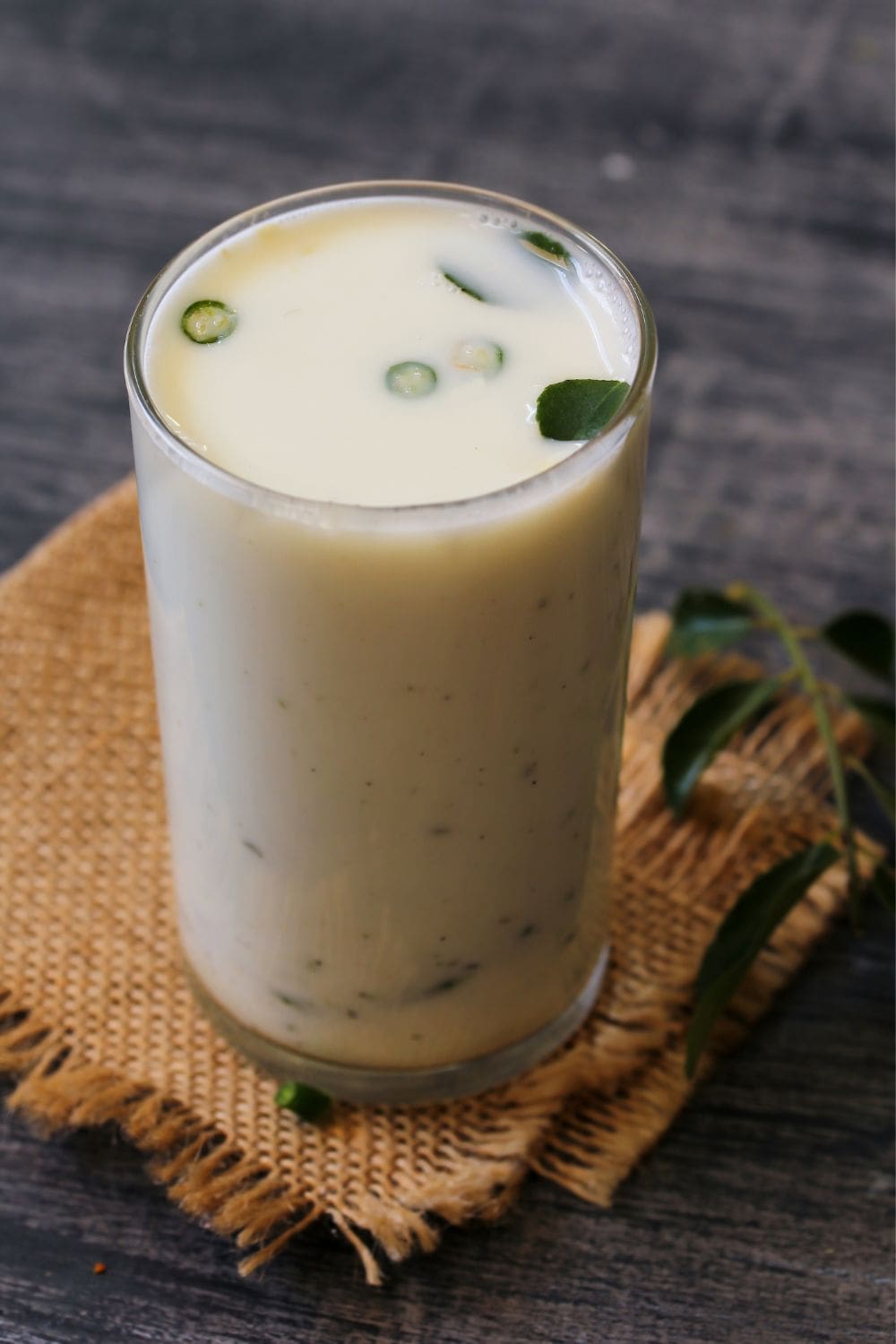 A glass of buttermilk on a napkin on a wooden table.
