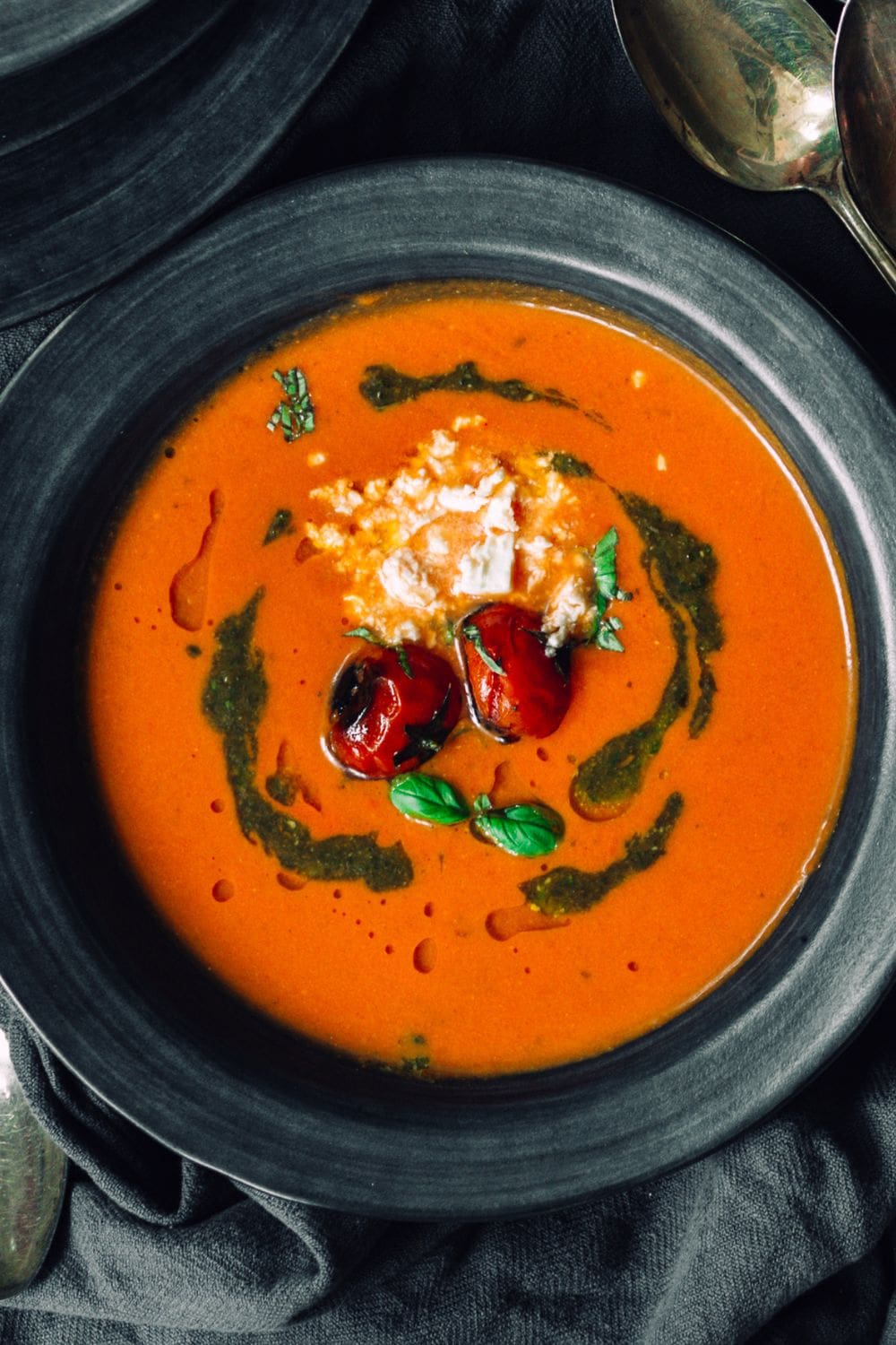 A plate of roasted tomato soup with feta cheese and basil pesto.