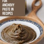 A small, white bowl filled with anchovy paste on a wooden table.