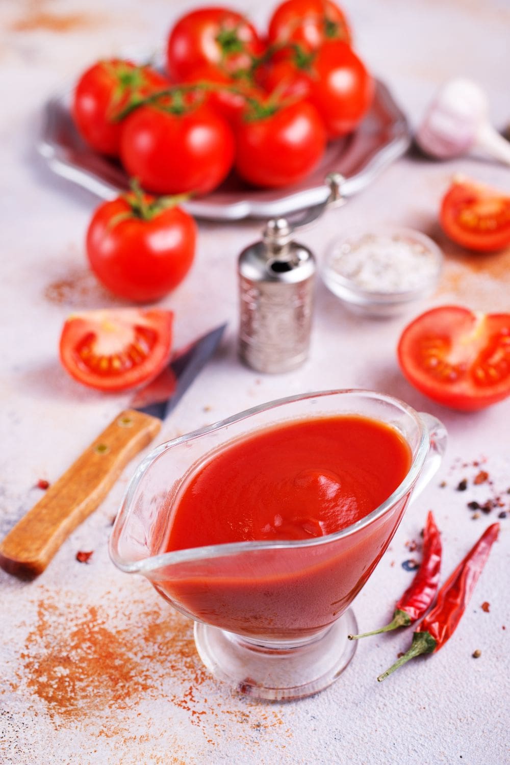 A close-up photo of a bowl of tomato sauce next to a plate of tomatoes.