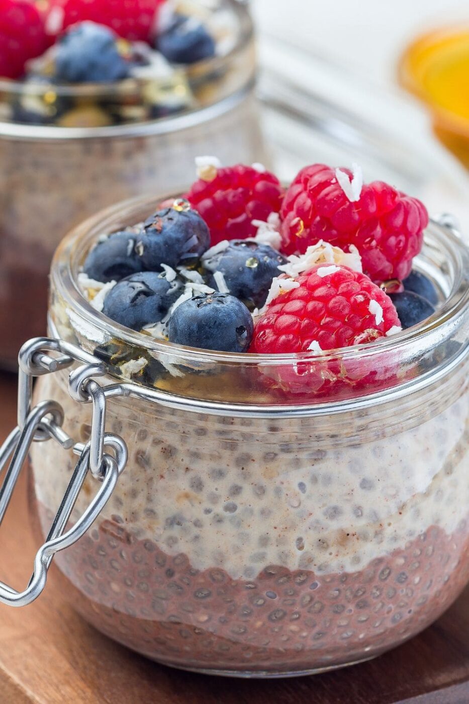 A glass jar filled with layers of chocolate and peanut butter chia pudding, garnished with berries or nuts.
