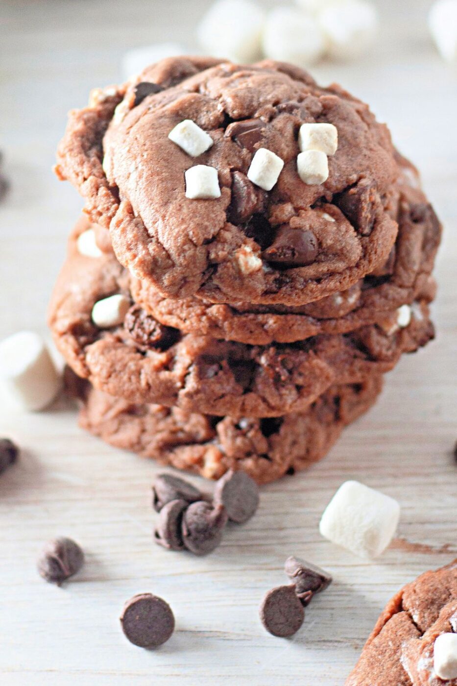 A pile of soft and chewy hot cocoa cookies with visible marshmallows and chocolate chips.