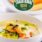 A white bowl filled with irish fish chowder sits on a wooden table.