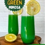 Two glasses of green mimosa with lemon slices on a wooden table.