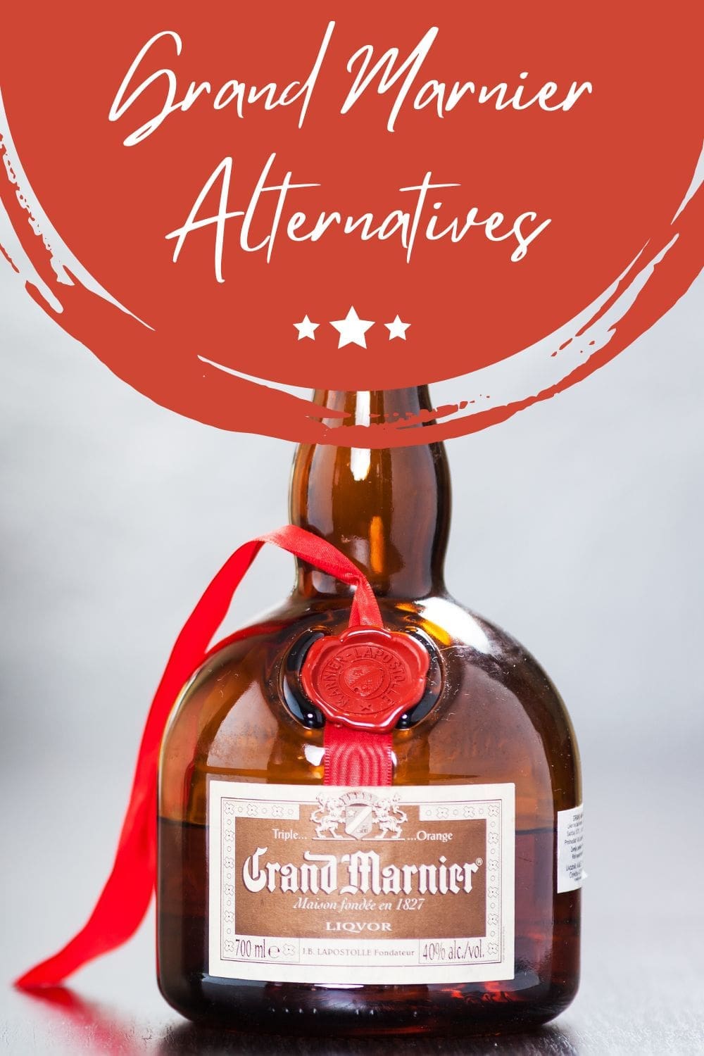A bottle of Grand Marnier liqueur with a red ribbon, sitting on a table.