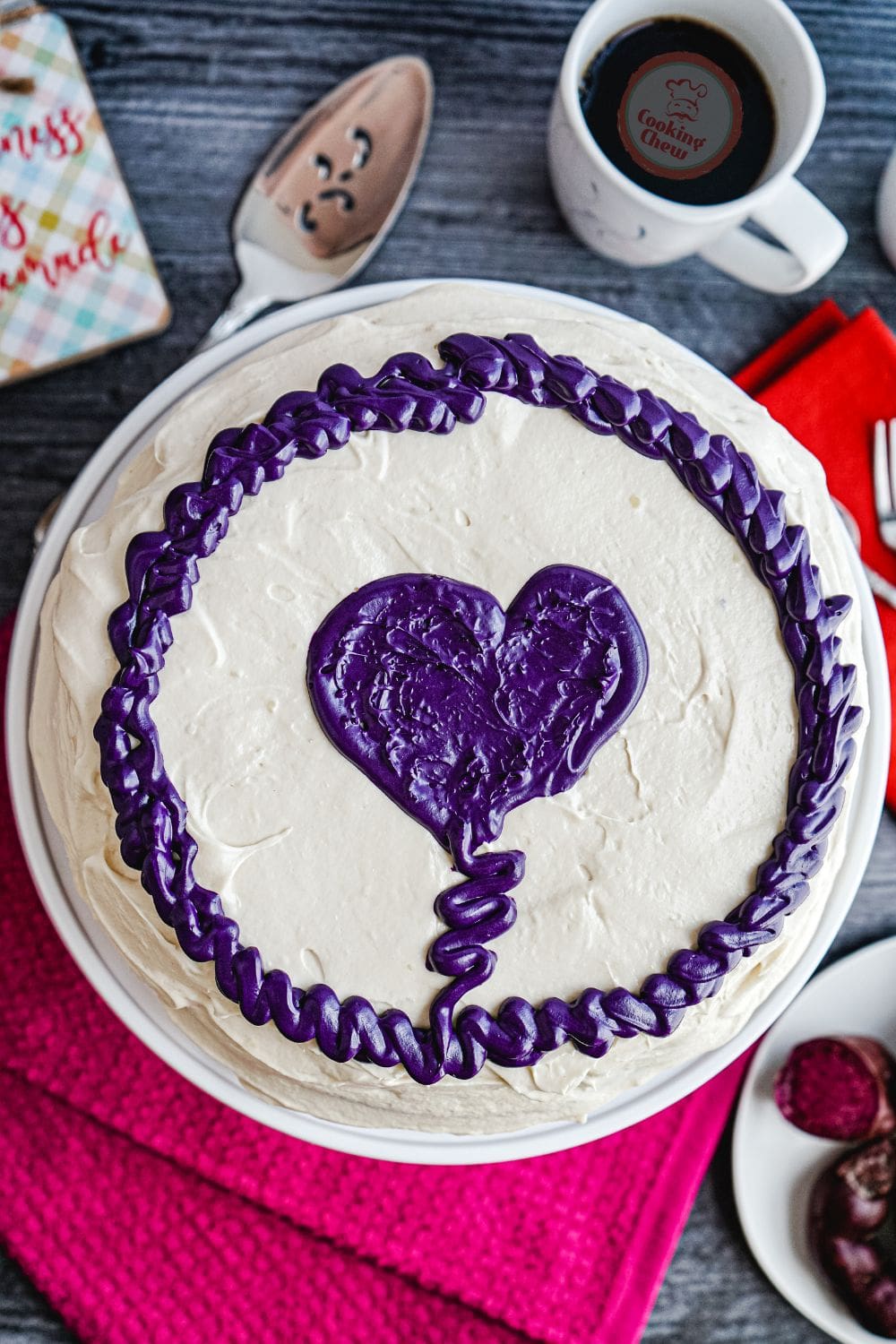 The image shows a whole ube cake with a purple frosting and a heart shape.