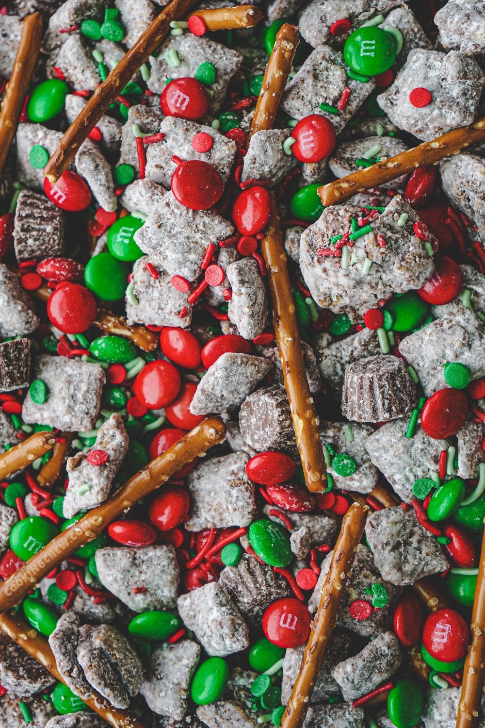 A bowl of Holiday-Themed Puppy Chow Mix, made with Chex cereal, peanut butter, powdered sugar, and festive sprinkles, such as Christmas M&Ms.