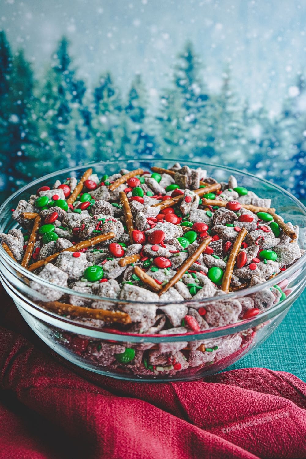 A bowl of red and green Christmas puppy chow, made with Chex cereal, peanut butter, powdered sugar, and festive red and green M&Ms.