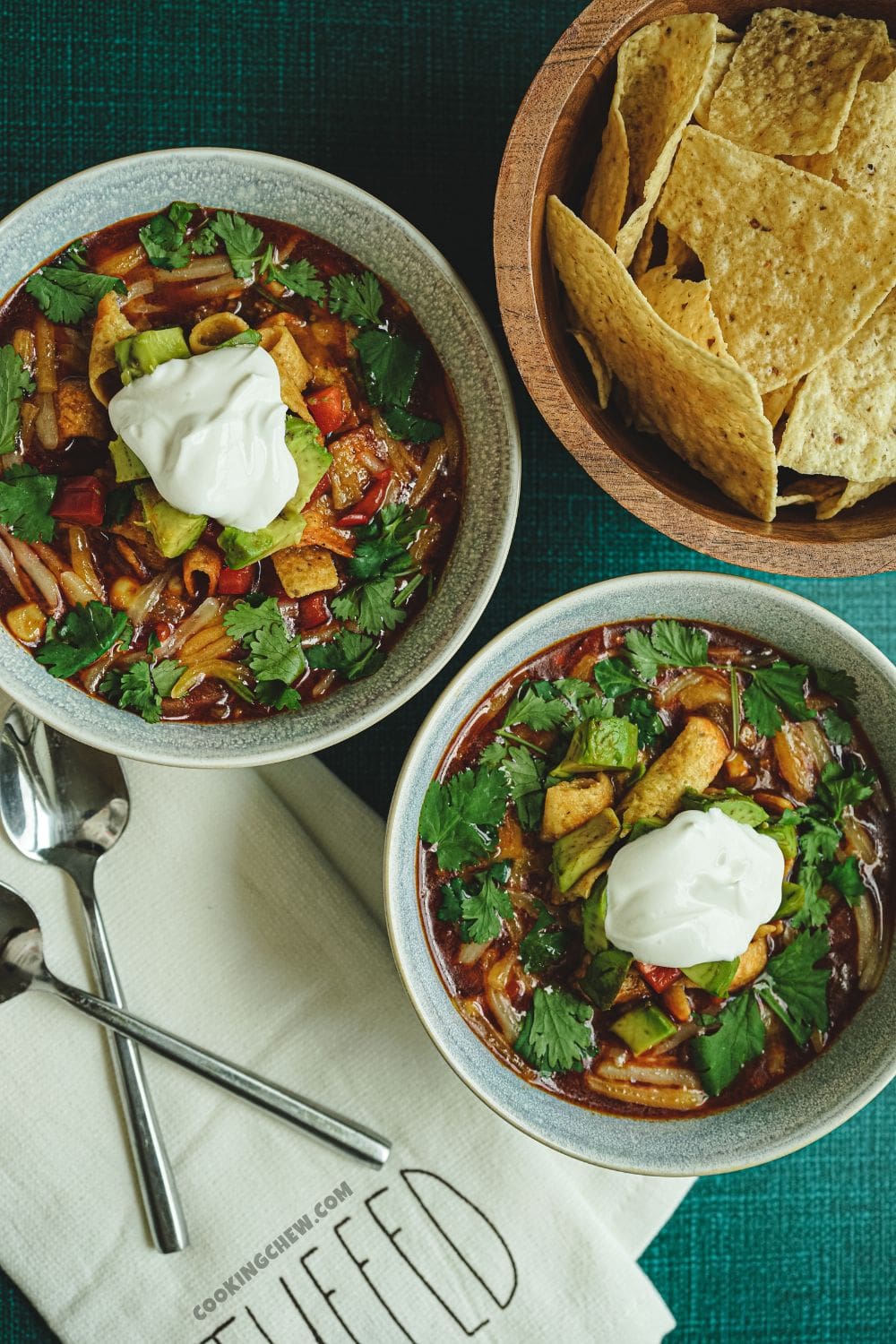 A mouthwatering photo of two steaming bowls of taco soup and a basket of tortilla chips, perfect for a cozy meal. 