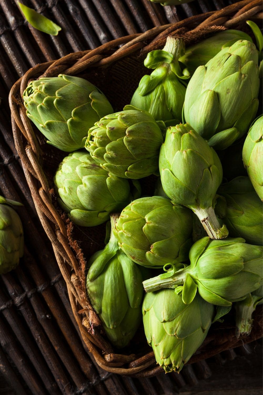 A wicker basket overflowing with green artichokes.