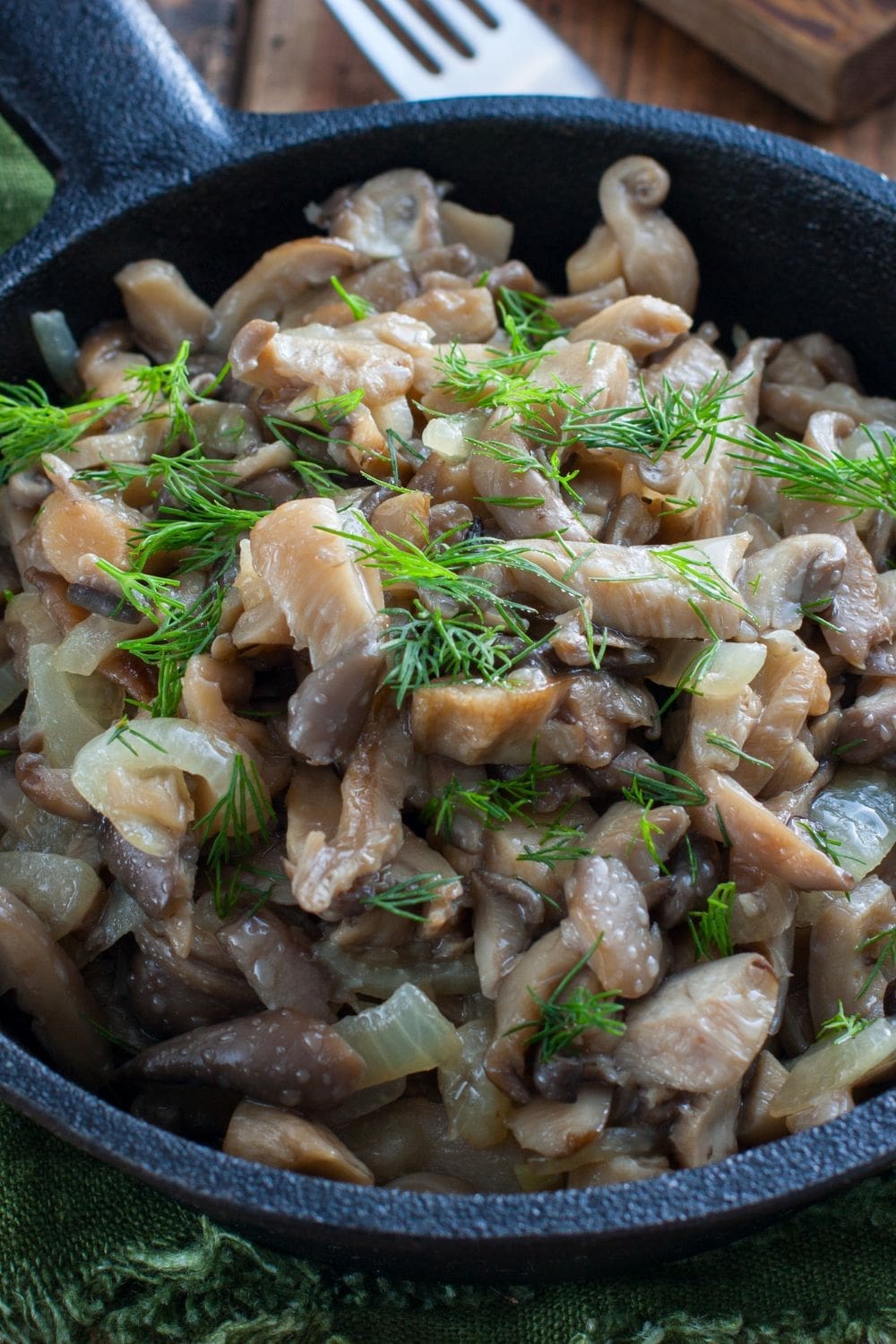 A skillet filled with sauteed oyster mushrooms, onions, and fresh dill. 