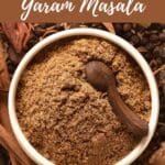 A bowl of garam masala powder with a wooden spoon.