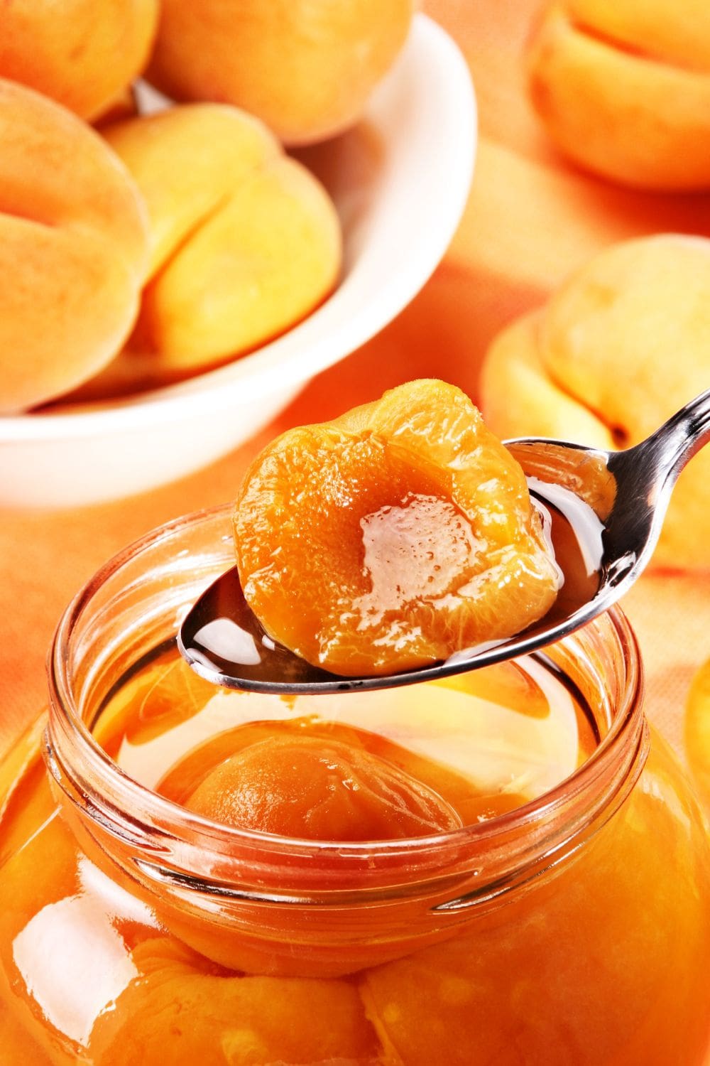 A close-up photo of an apricot preserve sits on a spoon.