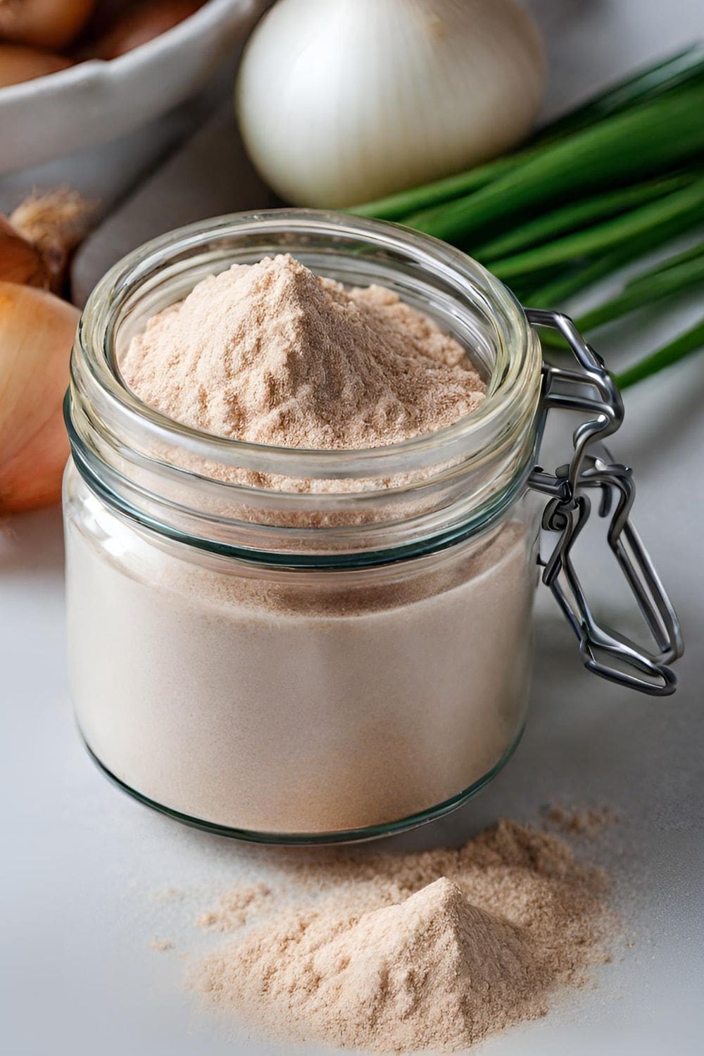 A glass jar of onion powder sits on a table. 