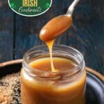 A close-up of a glass jar filled with caramel whiskey sauce.