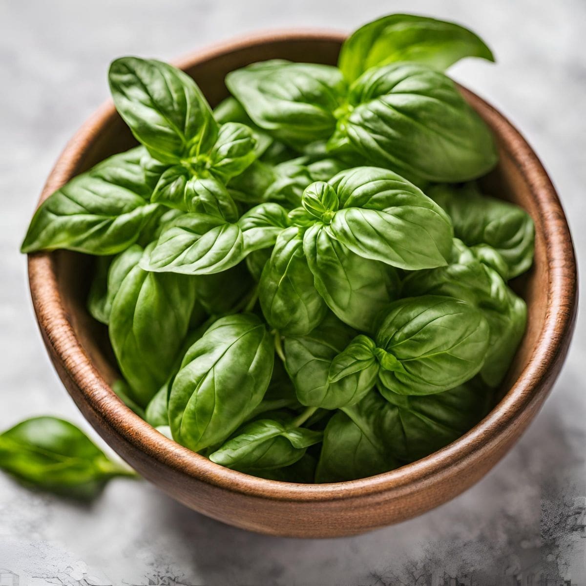 A rustic wooden bowl brimming with fresh basil leaves.