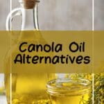 A clear glass bottle filled with canola oil sits on a light wood table, next to a small white ceramic bowl also filled with canola oil.