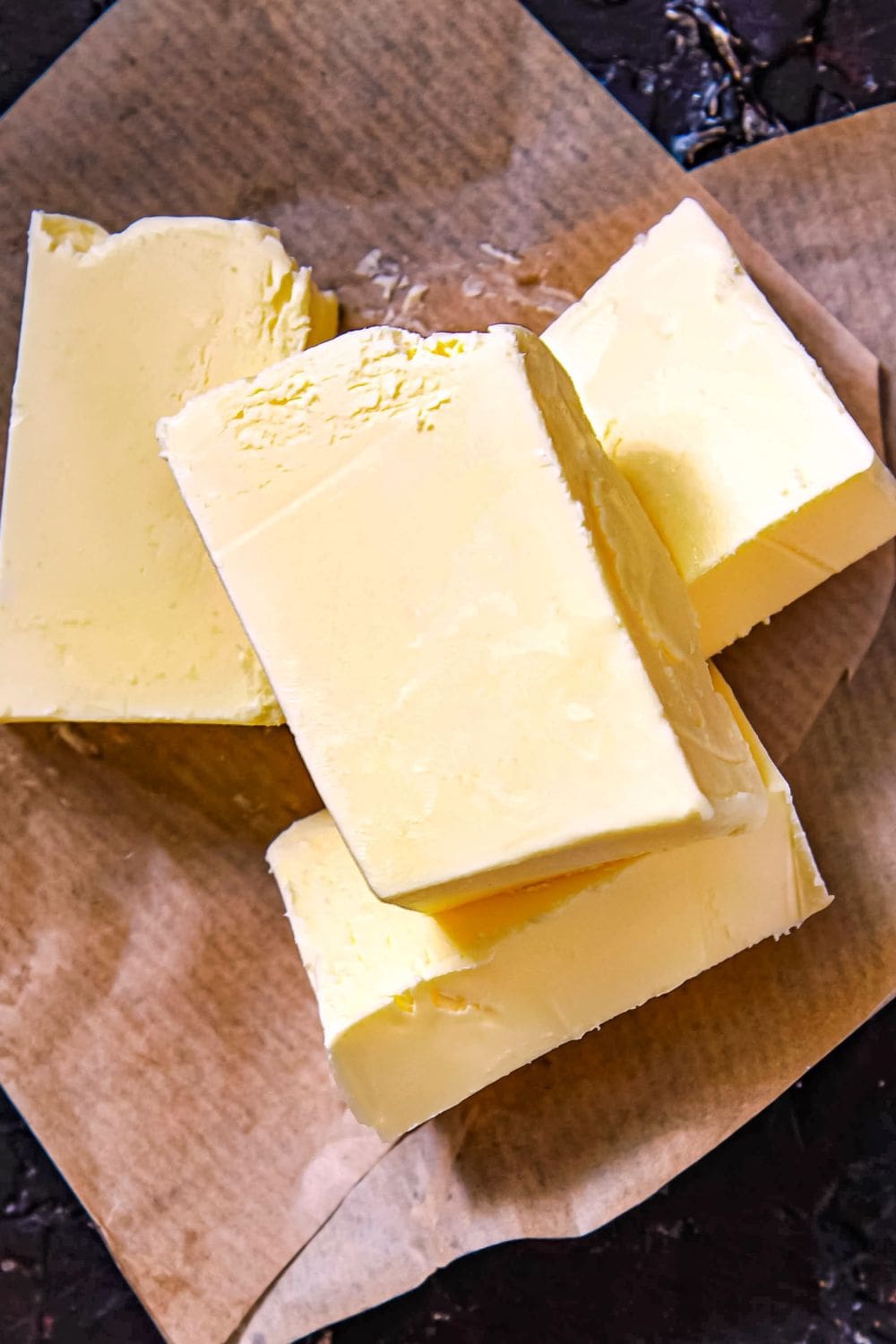 A close-up photo of four pats of butter on a brown paper sheet. 