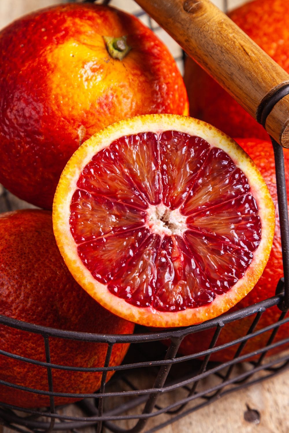A close-up view of a halved blood orange in a wire basket. 