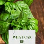 A close-up photo of a bunch of fresh basil leaves on a wooden cutting board.