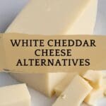 A block of white cheddar cheese rests on a simple white plate.