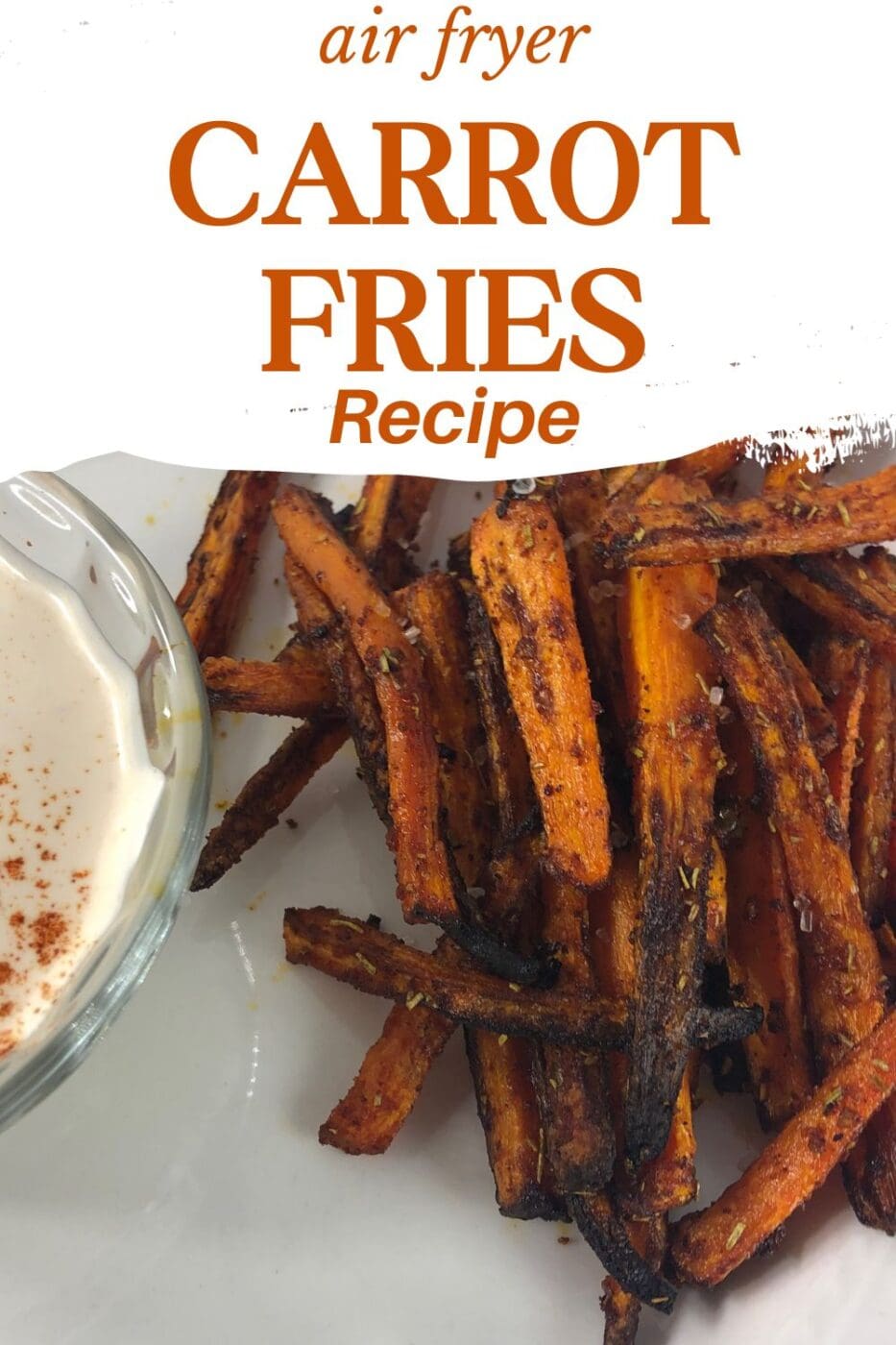 Carrot fries on a white plate with dipping sauce in a glass bowl on the side.