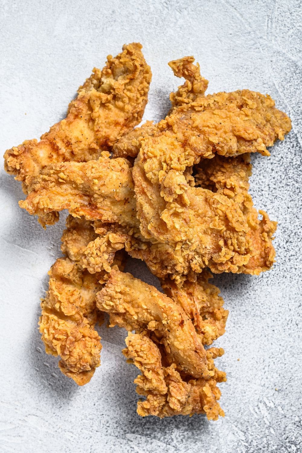 A close-up photo of crispy chicken breast strips coated in flavorful funyuns.