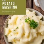 A close-up photo of a bowl of mashed potatoes on a wooden table.