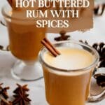 A close-up photo of a steaming cup of spiced hot buttered rum with cinnamon sticks and star anise pods on a saucer.