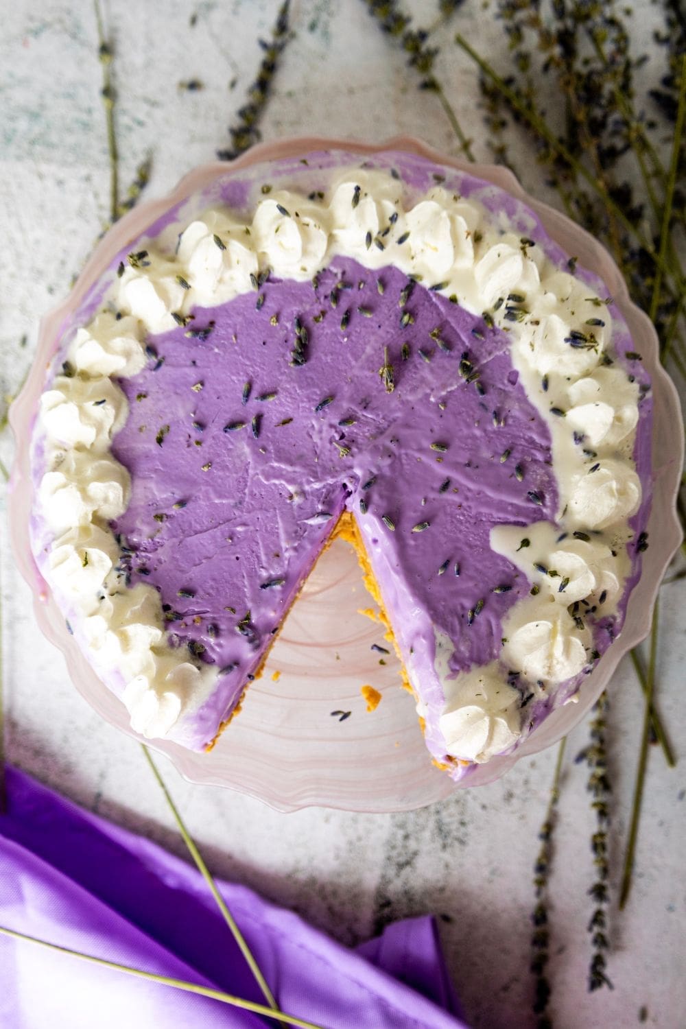 A photo of lavender cake topped with whipped cream and lavender flowers.