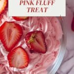 A bowl of pink whipped dessert resembling Jello salad, with whole strawberries on top.