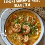 A bowl of lemony shrimp and white bean stew sits on a wooden table.