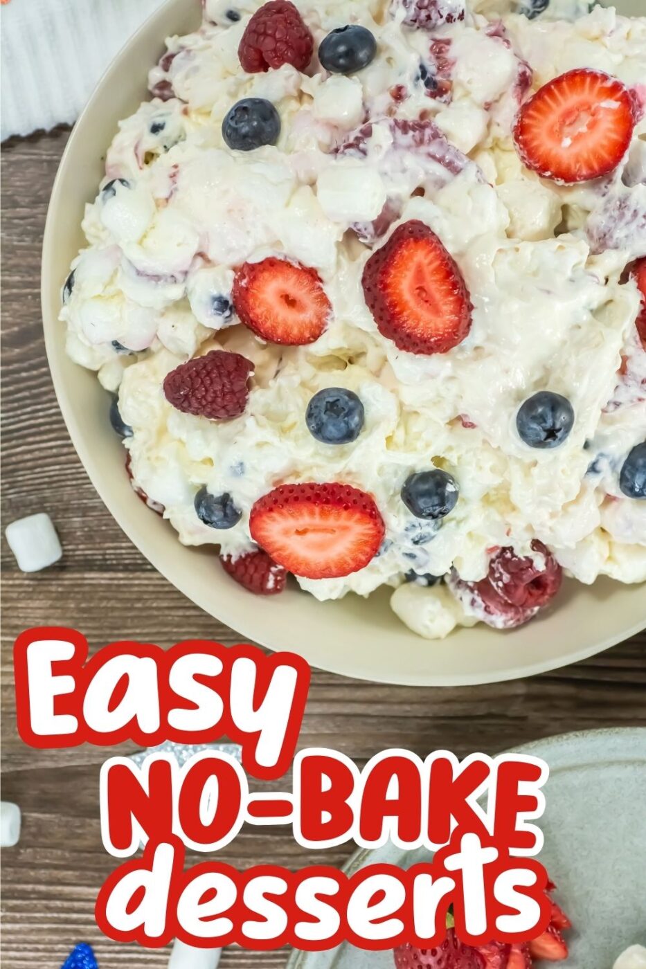 Close up of a white bowl with a fruit salad containing cheesecake ingredients plus blueberries, raspberries and strawberries.