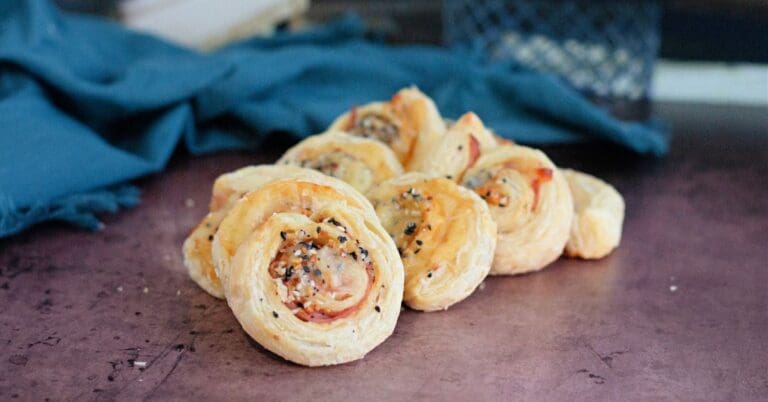 Closeup of baked puff pastry filled with sliced ham and melted cheese.