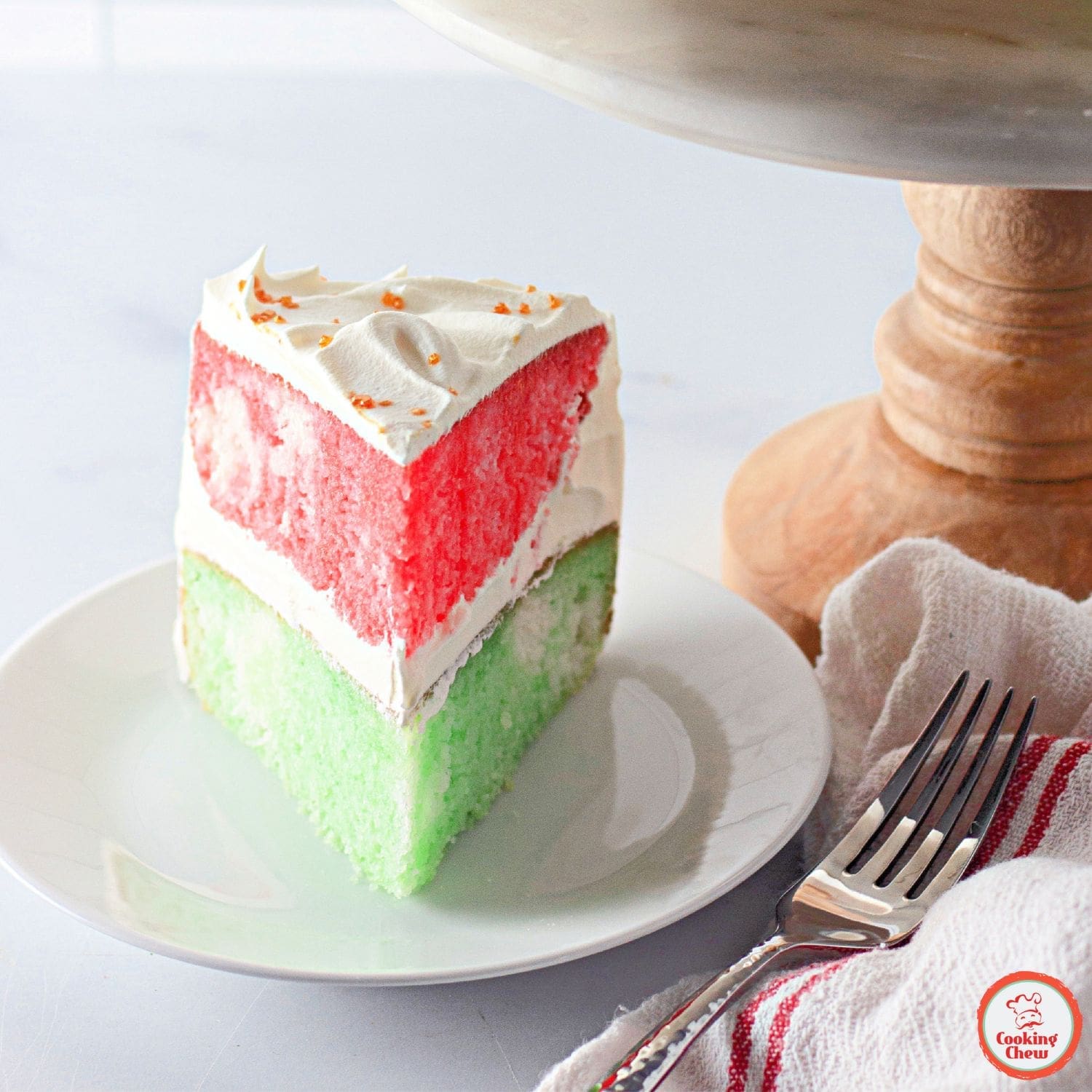 Christmas Jello cake with red and green layers on a holiday-themed table.