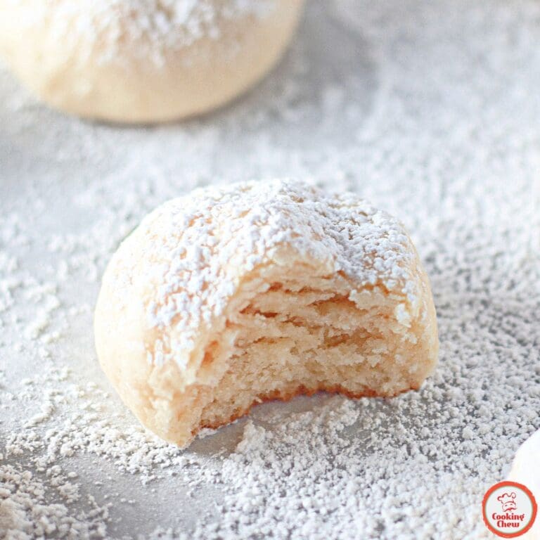 Festive cream cheese cookies dusted with powdered sugar on a holiday-themed table.