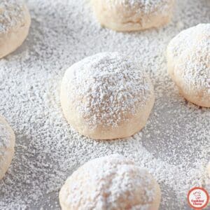 Close-up of cream cheese cookies on a cooling rack, lightly sprinkled with powdered sugar.