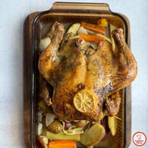 Perfectly roasted whole chicken, golden brown with vegetables.