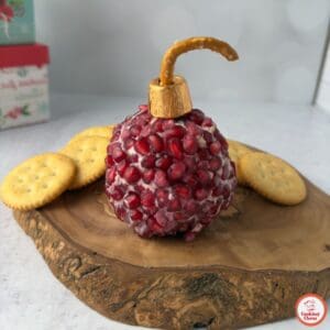 A Christmas-themed cheese ball with pomegranate seeds and a festive design.