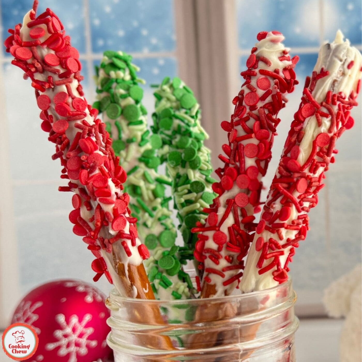 A tray of festive pretzel rods dipped in chocolate and topped with sprinkles.