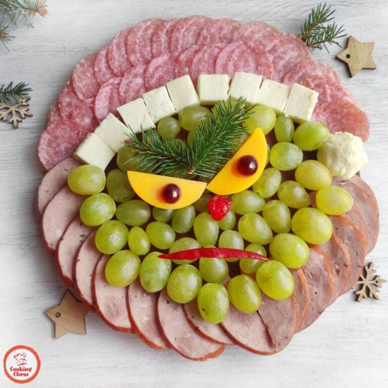 A holiday charcuterie board with Grinch-inspired snacks for Christmas parties.