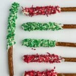 Chocolate-covered pretzel rods decorated with red and green candy sprinkles.