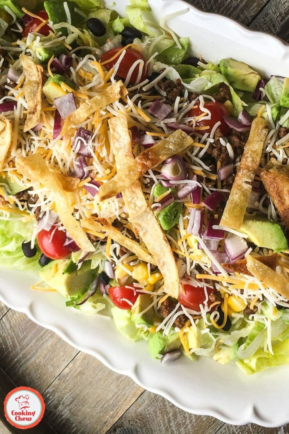 A vibrant beef taco salad with seasoned ground beef, crisp lettuce, juicy tomatoes, shredded cheese, and creamy dressing served in a bowl.