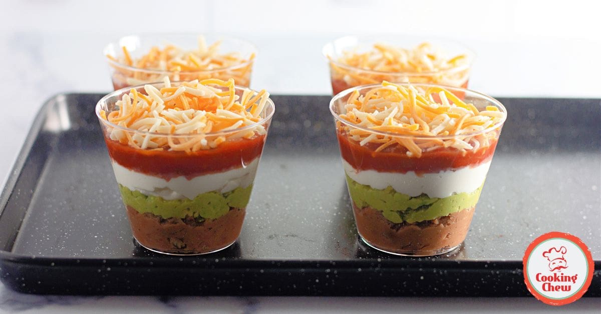 Game day spread featuring 7 layer dip cups with chips and salsa.