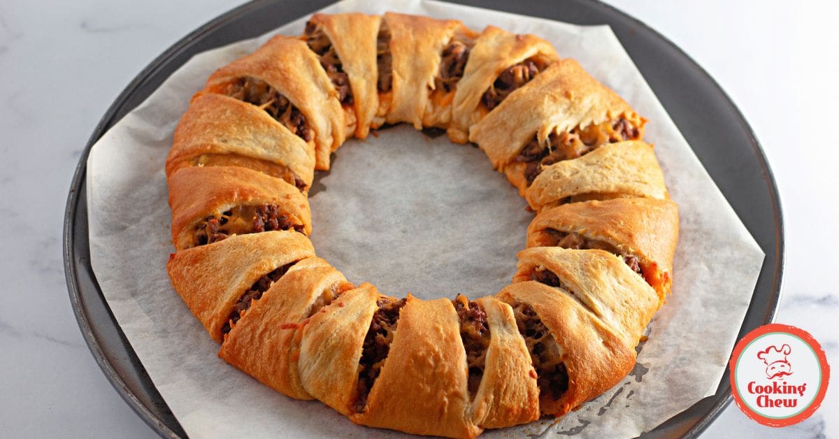 A taco crescent ring with golden crust and a side of sour cream.