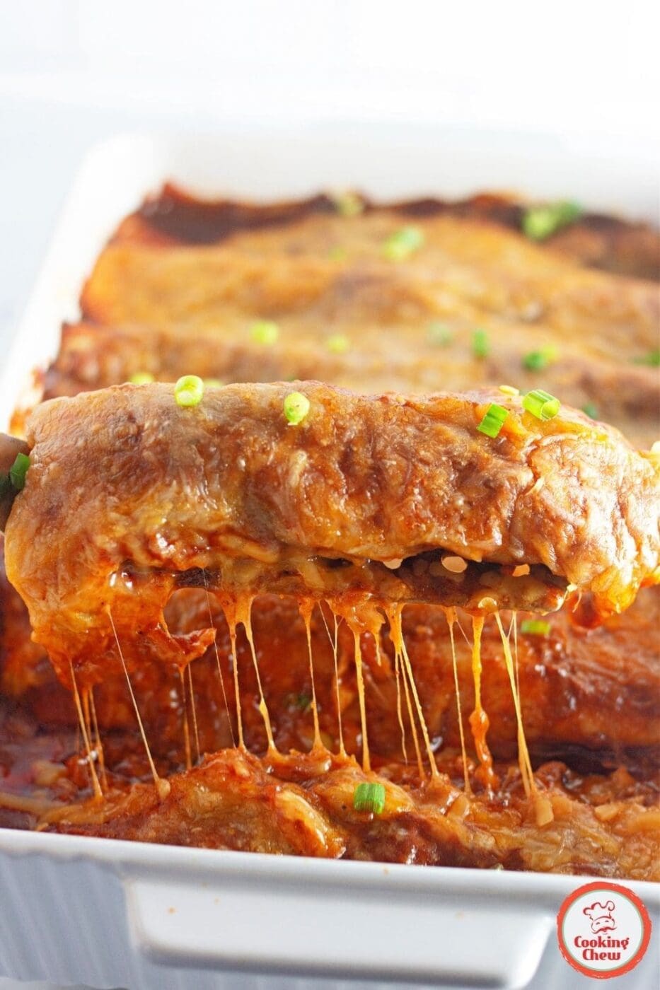 A pan of cheesy beef enchiladas topped with homemade enchilada sauce and garnished with fresh cilantro, ready to serve.