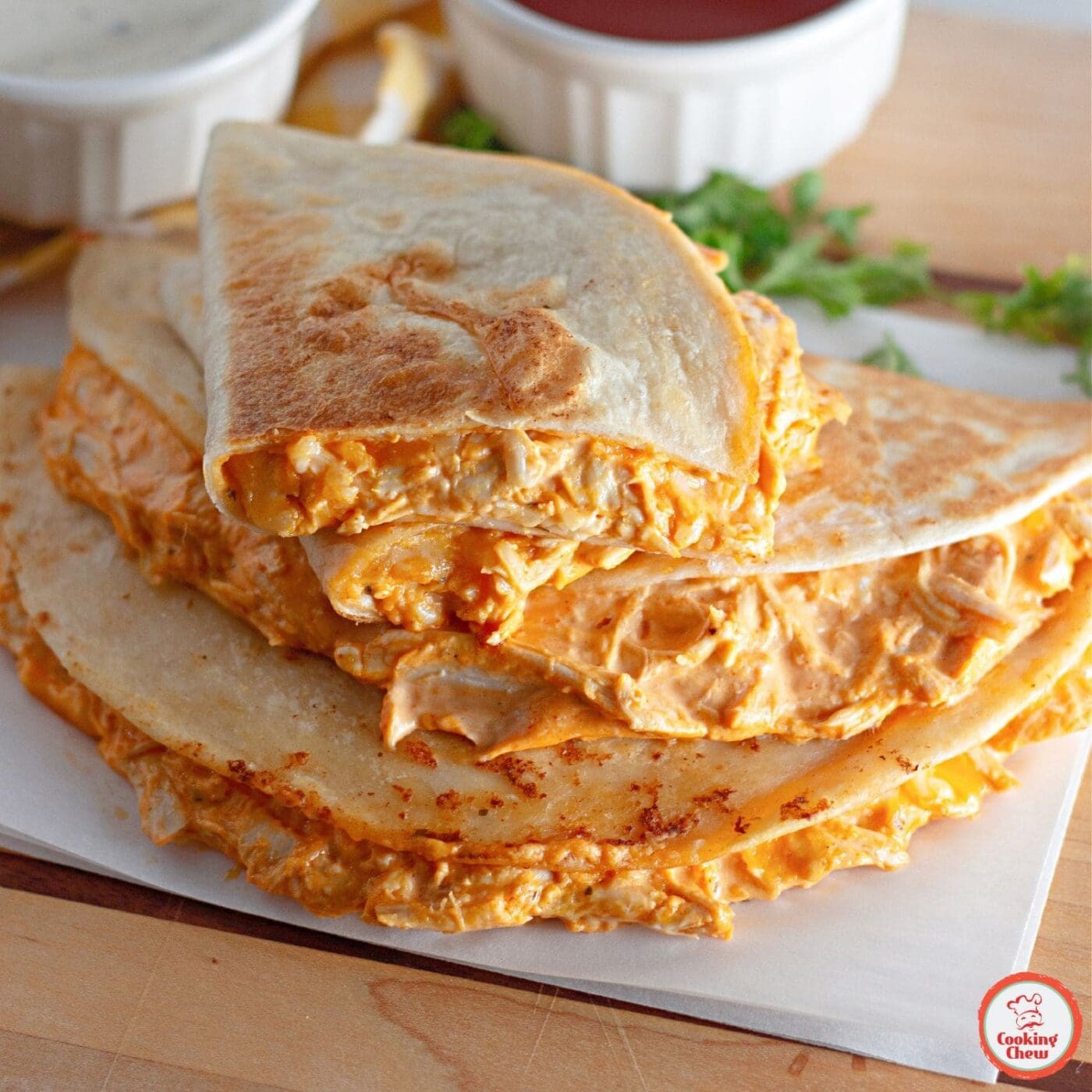 A serving plate of buffalo chicken quesadillas with a side of ranch.