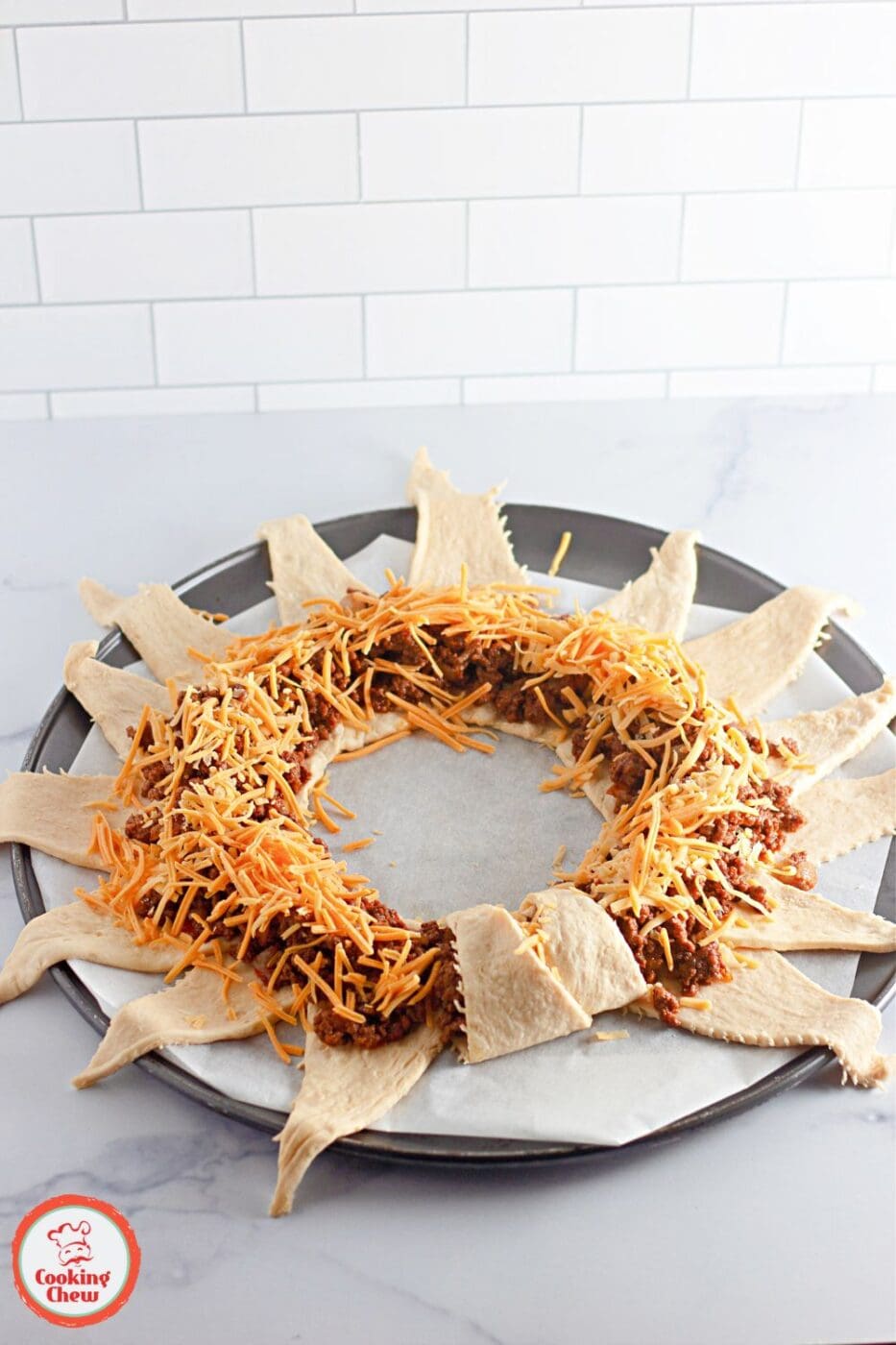 A golden crescent roll taco ring filled with seasoned ground beef and melted cheese.